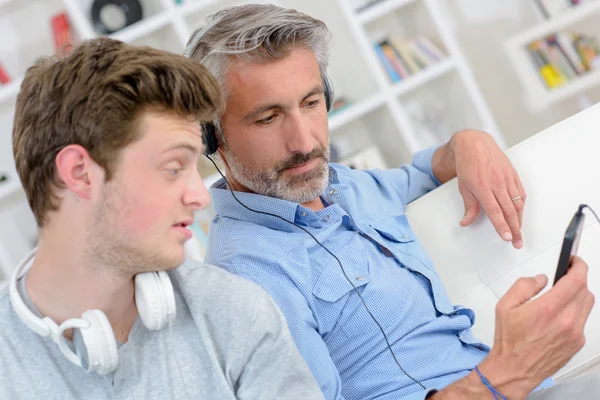 Man showing mp3 screen to son who looks uninterested — Stock Photo, Image
