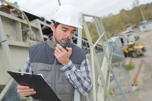 Mannen i byggarbetsplatsen med Urklipp och walkie talkie — Stockfoto