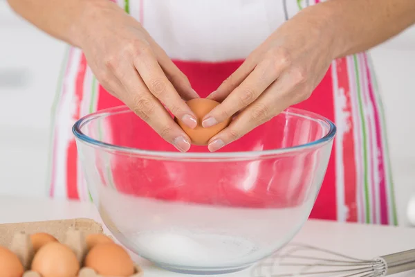 Женщина разбивает яйцо для выпечки — стоковое фото
