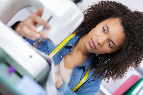 Jonge mooie vrouw met naaimachine in haar kantoor — Stockfoto