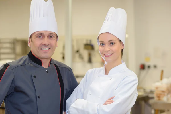 Samec a samice šéfkuchař pózuje v kuchyni restaurace — Stock fotografie