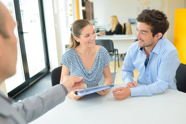 Agents immobiliers transmettant les clés au jeune couple — Photo