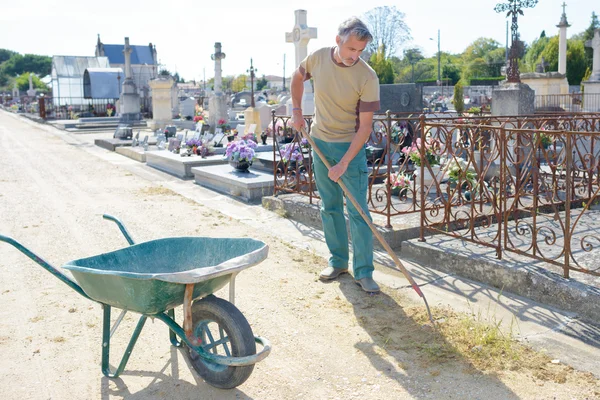 Muž, odstraňování plevele kolem hrobů — Stock fotografie