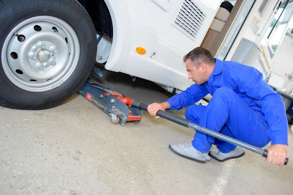 Mechanic pushing jack under vehicle — Stock Photo, Image