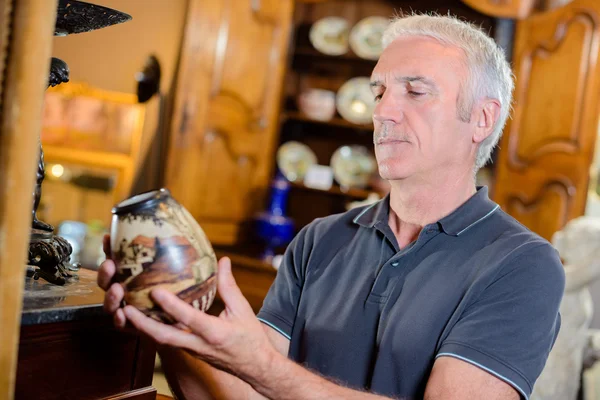 Uomo esaminando un vaso antico — Foto Stock