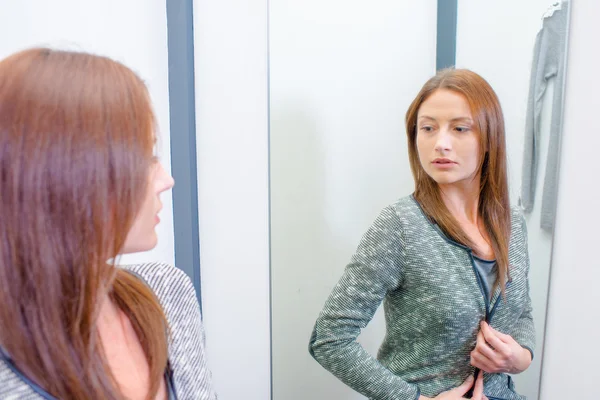 Lady trying on top in fitting room — Stock Photo, Image