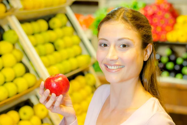 Senhora na loja segurando maçã vermelha — Fotografia de Stock