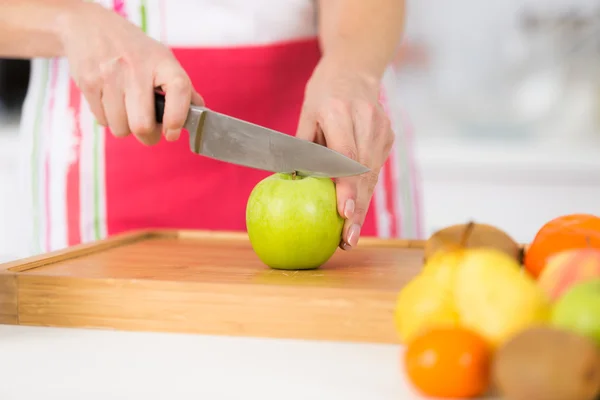 Primer plano en manos femeninas maduras rebanando manzanas en la tabla de cortar — Foto de Stock