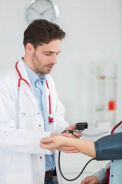 Médico com casaco branco tomando pacientes pressão arterial — Fotografia de Stock