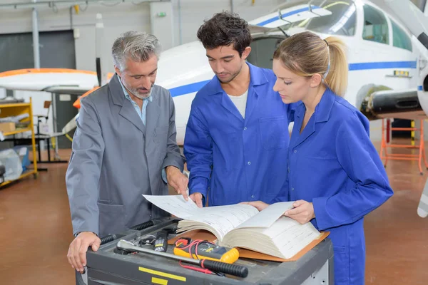 Engenheiros olhando através de manual — Fotografia de Stock