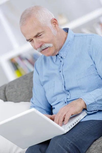 Старший використовує ноутбук вдома — стокове фото