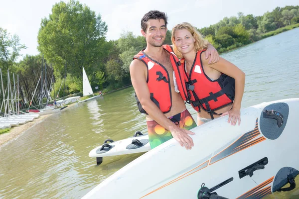 Pareja abrazándose al lado de la tabla de surf — Foto de Stock