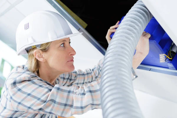 Female worker fitting ventilation system in buildings ceiling — Stock Photo, Image