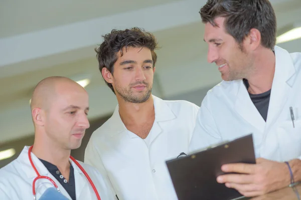 Três médicos olhando para a área de transferência — Fotografia de Stock