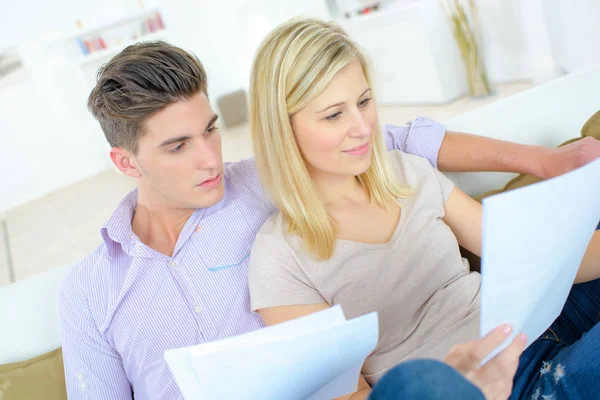 Pareja leyendo a través de un contrato en el sofá —  Fotos de Stock