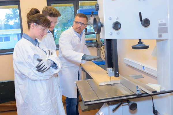 Timmerman en leerlingen snijden van hout — Stockfoto