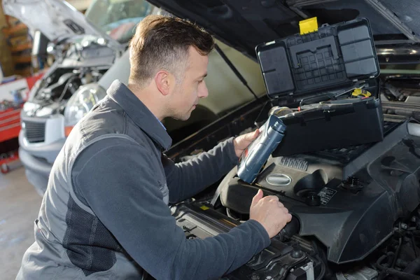 Meccanico auto sostituzione olio su motore in garage — Foto Stock