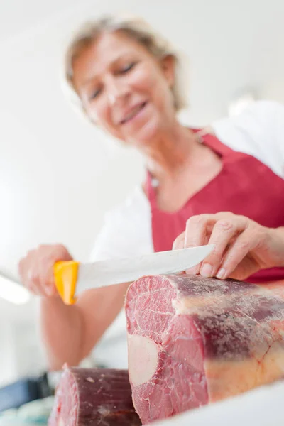 Carniceiro fêmea cortando carne — Fotografia de Stock