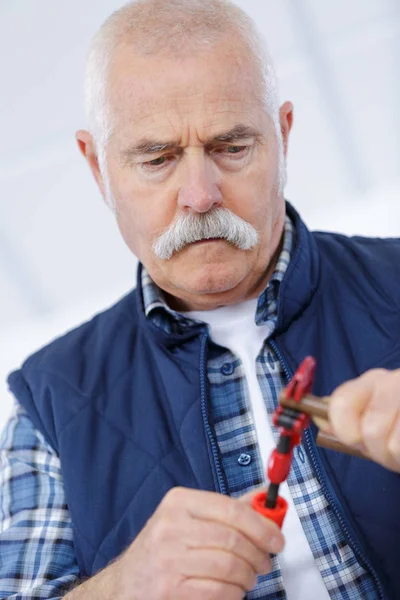 Senior handyman trying to fix something — Stock Photo, Image