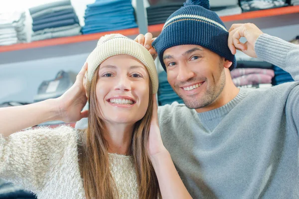 Paar in winkel proberen op hoeden van beeny — Stockfoto