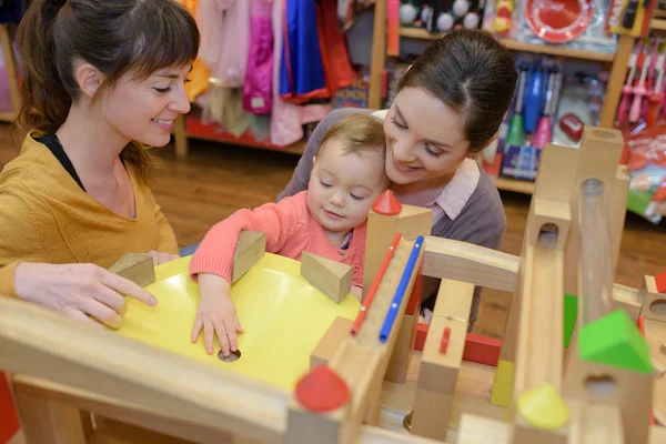 Mère et fille avec vendeur attrayant dans le magasin de jouets — Photo