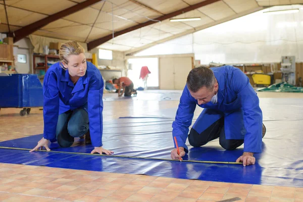 Zwei Arbeiter messen Material auf dem Fußboden — Stockfoto