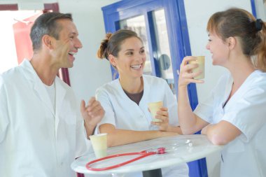 Medical staff laughing and drinking coffee clipart