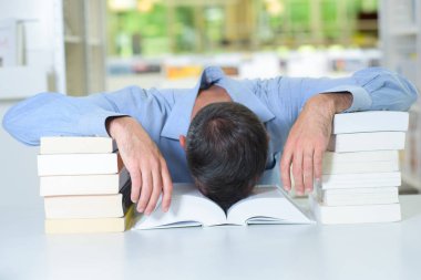 Man with head slumped in a book clipart
