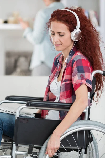 Gehandicapte vrouw met laptop en hoofdtelefoon ontspannen thuis — Stockfoto