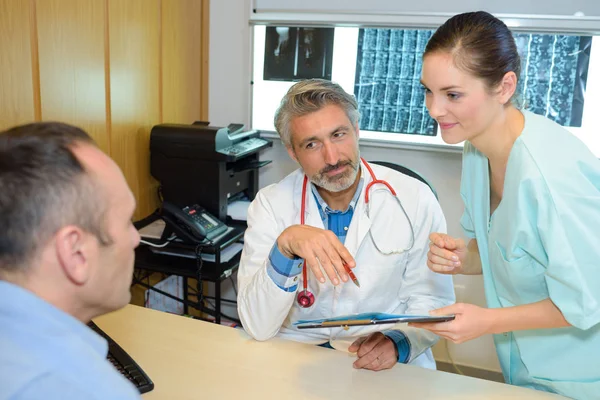 Médico e enfermeiro conversando com paciente do sexo masculino — Fotografia de Stock