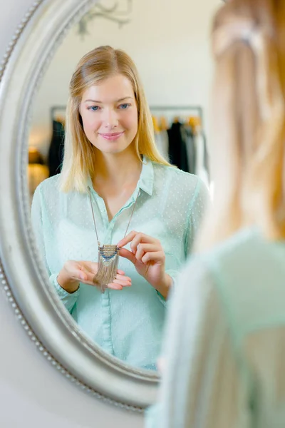 Kobieta próbuje na naszyjnik przed lustrem — Zdjęcie stockowe