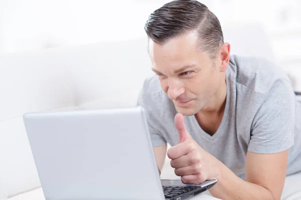 Homem segurando laptop e polegares para cima interior — Fotografia de Stock