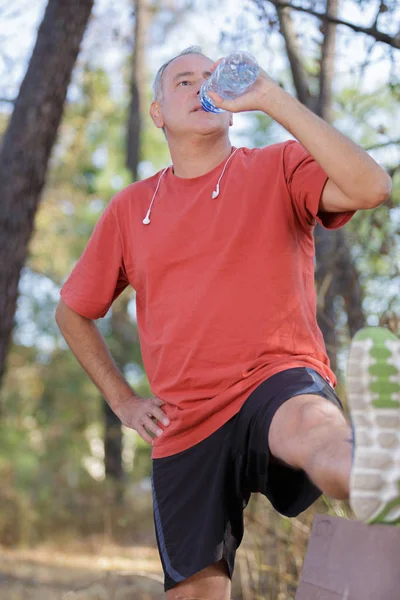 Атлетичный взрослый мужчина пьет воду из бутылки — стоковое фото