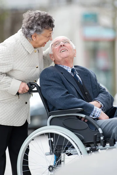 Senior mit Frau im Rollstuhl draußen in der Stadt — Stockfoto