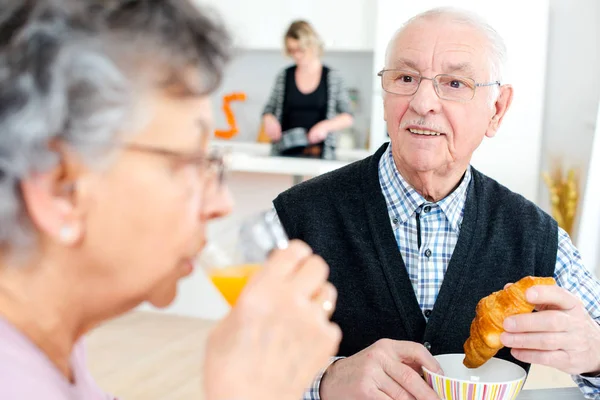 Happy senior couple with glasses of orange juice — Stock Photo, Image