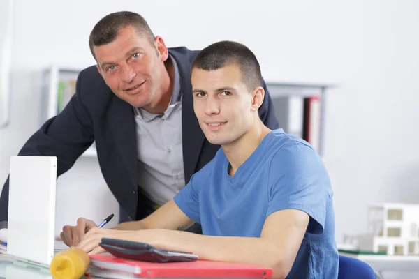 Lärare att hjälpa College Student med studier i biblioteket — Stockfoto