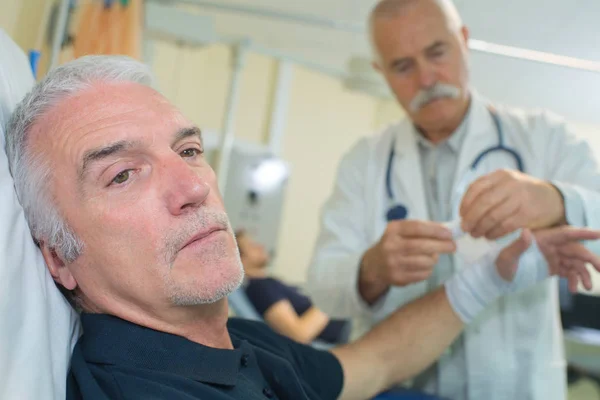 senior doctor putting a bandage on an elder mans arm