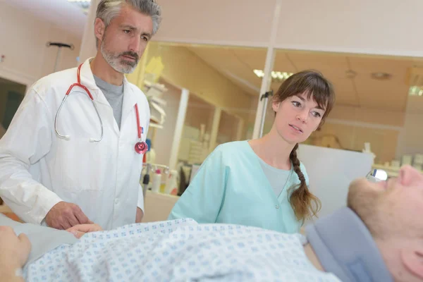 Médico e enfermeiro interagindo uns com os outros no quarto do hospital — Fotografia de Stock