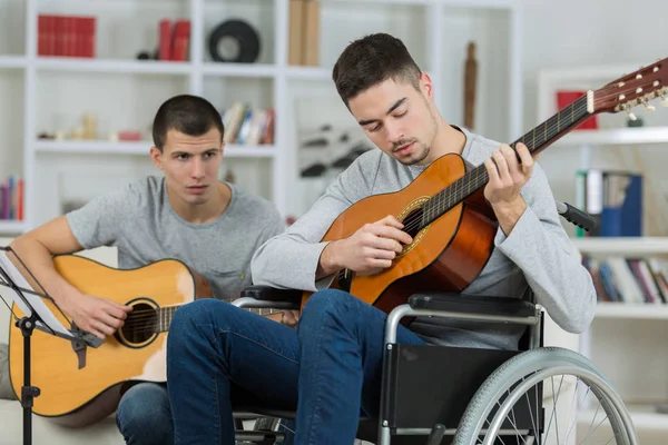 Gehandicapte tiener gitaarspelen met zijn vriend — Stockfoto