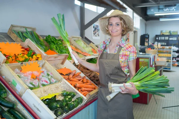 Leende kvinna personal holding gäng purjolök i organiska avsnitt — Stockfoto