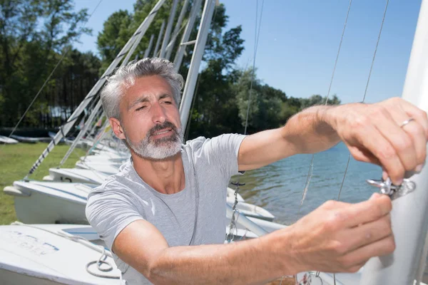 Attractive middle-aged man preparing sport sailboat — Stock Photo, Image