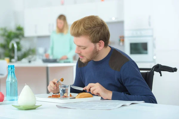 Інвалідний чоловік їсть з дружиною на задньому плані — стокове фото