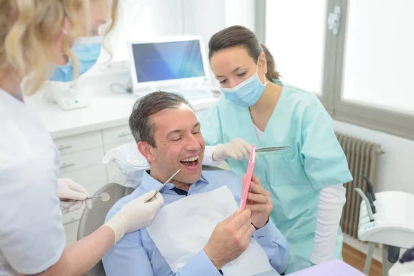 Paziente di sesso maschile e dentista con assistente durante il check up — Foto Stock