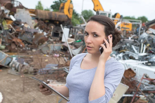 Mujer en el patio de chatarra utilizando el teléfono móvil —  Fotos de Stock