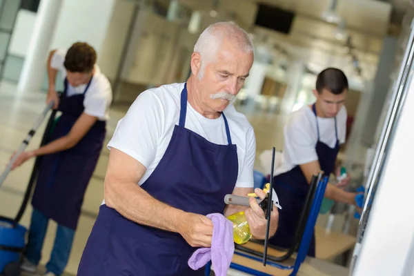 Mature man cleaning building with younger team — Stock Photo, Image