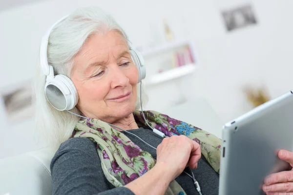 Szczęśliwa kobieta starszy słuchanie muzyki na cyfrowy tablicowy — Zdjęcie stockowe
