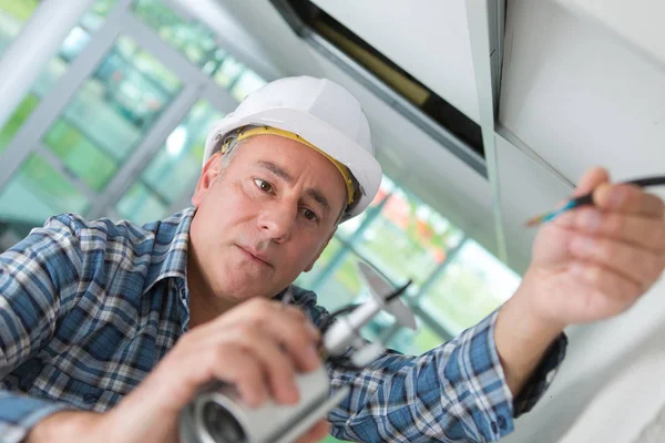 Vecchio lavoratore in casco bianco riparazione — Foto Stock