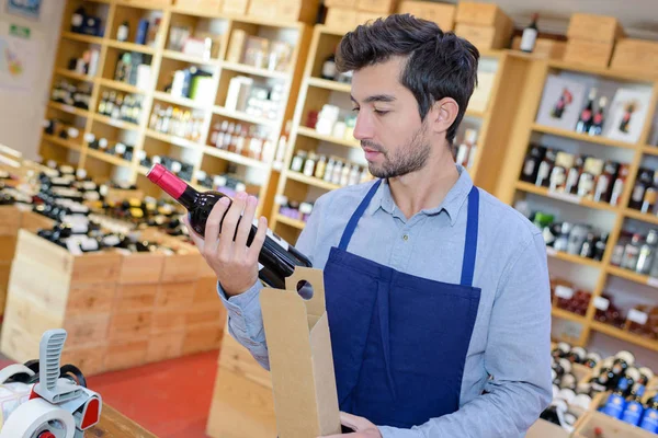 wine merchant who checks the label of a bottle