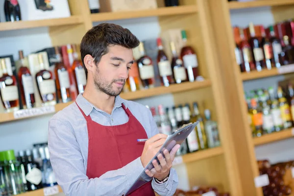 Confident young sommelier writing something at his note pad — Stock Photo, Image