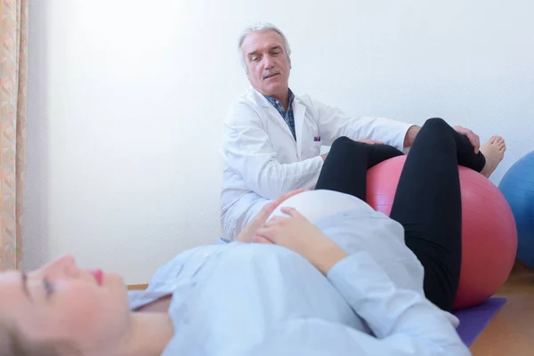 Ärztin mit schwangerer Frau mit Gymnastikball — Stockfoto